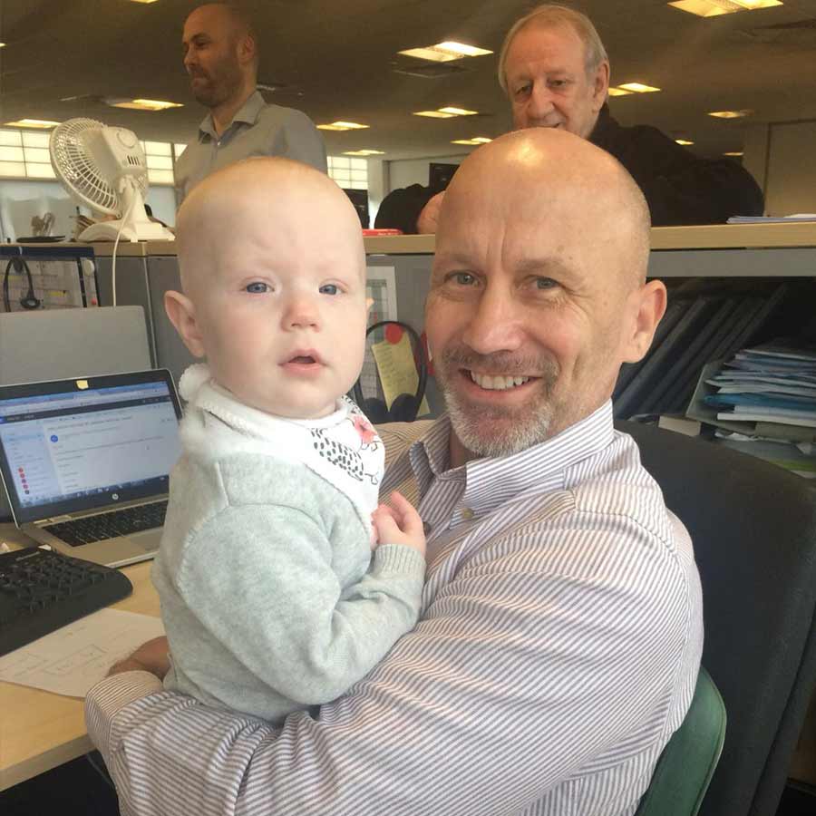 A male client holding a baby in an office environment
