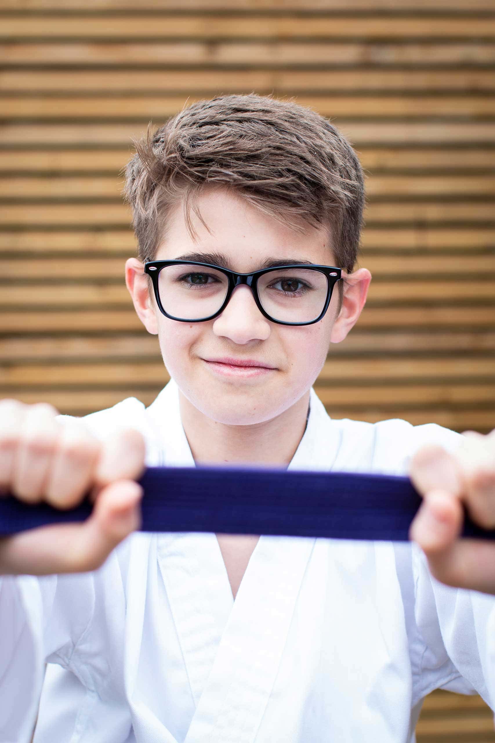 Teen Photos - Teenage boy holding purple karate belt in front of the camera