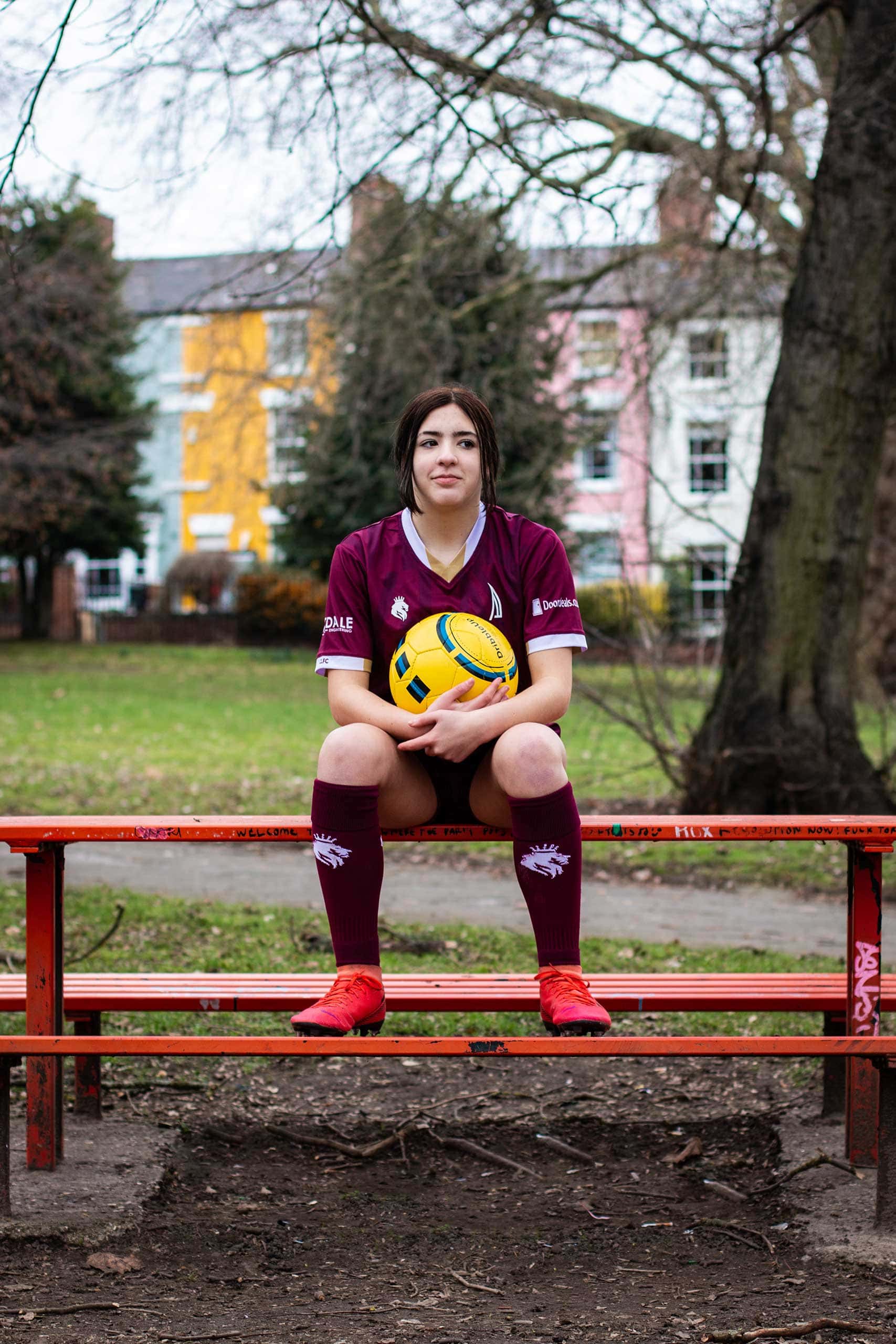 Teen Photos - Teenage girl sitting on park bench table holding football